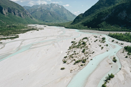 Scenic view of a winding river through a wide, sandy valley with mountains in the background, symbolizing a break from the daily IT routine.