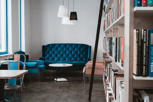 Cozy office lounge with blue sofa and bookshelves, ideal for planning hilarious pranks to boost team morale.