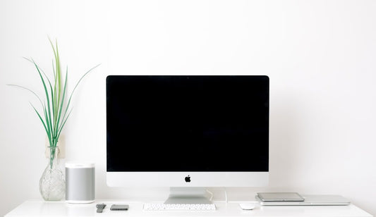 Minimalist office desk setup with an iMac, plants, and accessories; perfect for executing lighthearted office pranks.